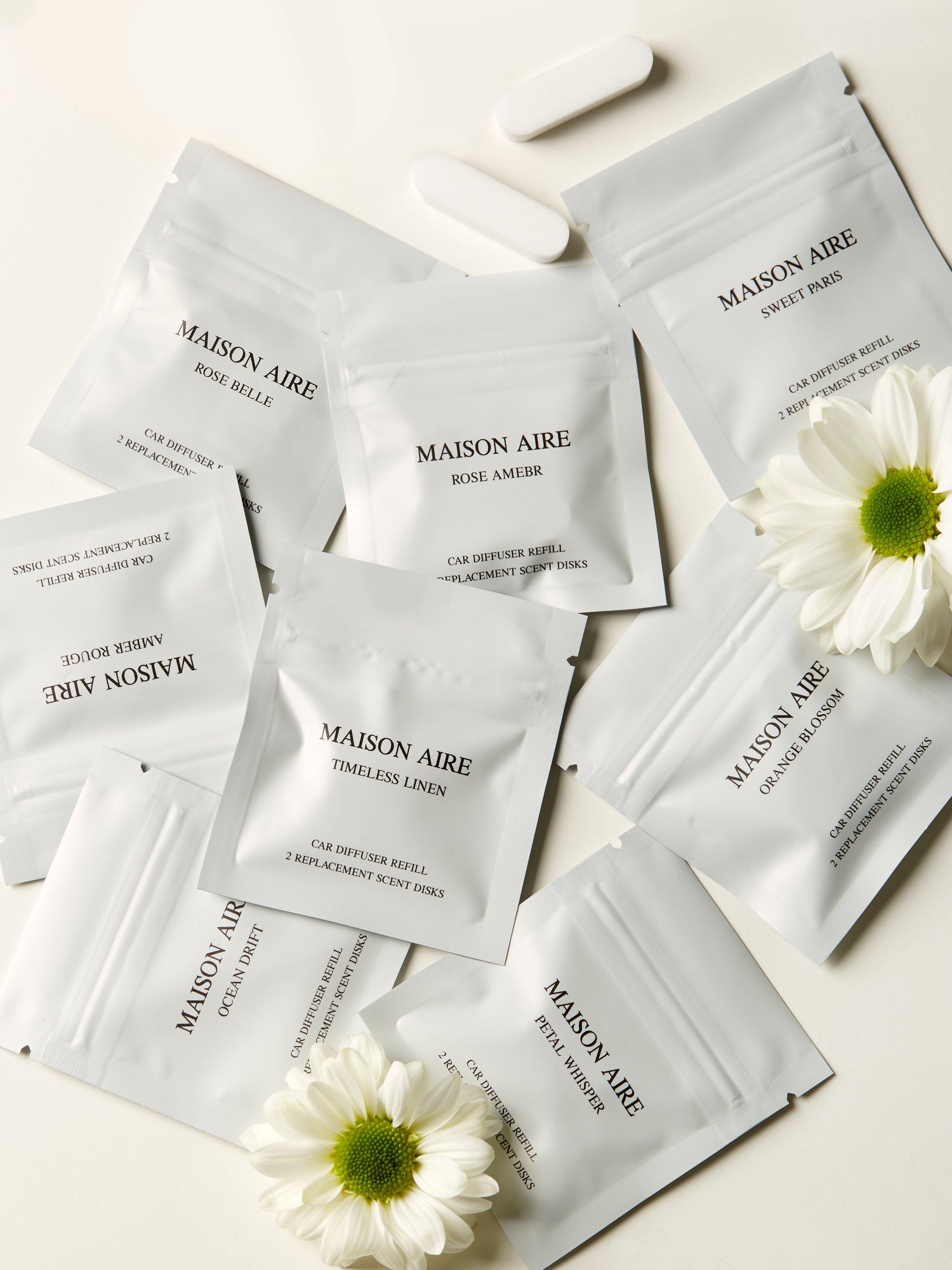 Maison Aire car diffuser refill scent disks in various fragrances with white flowers on cream background