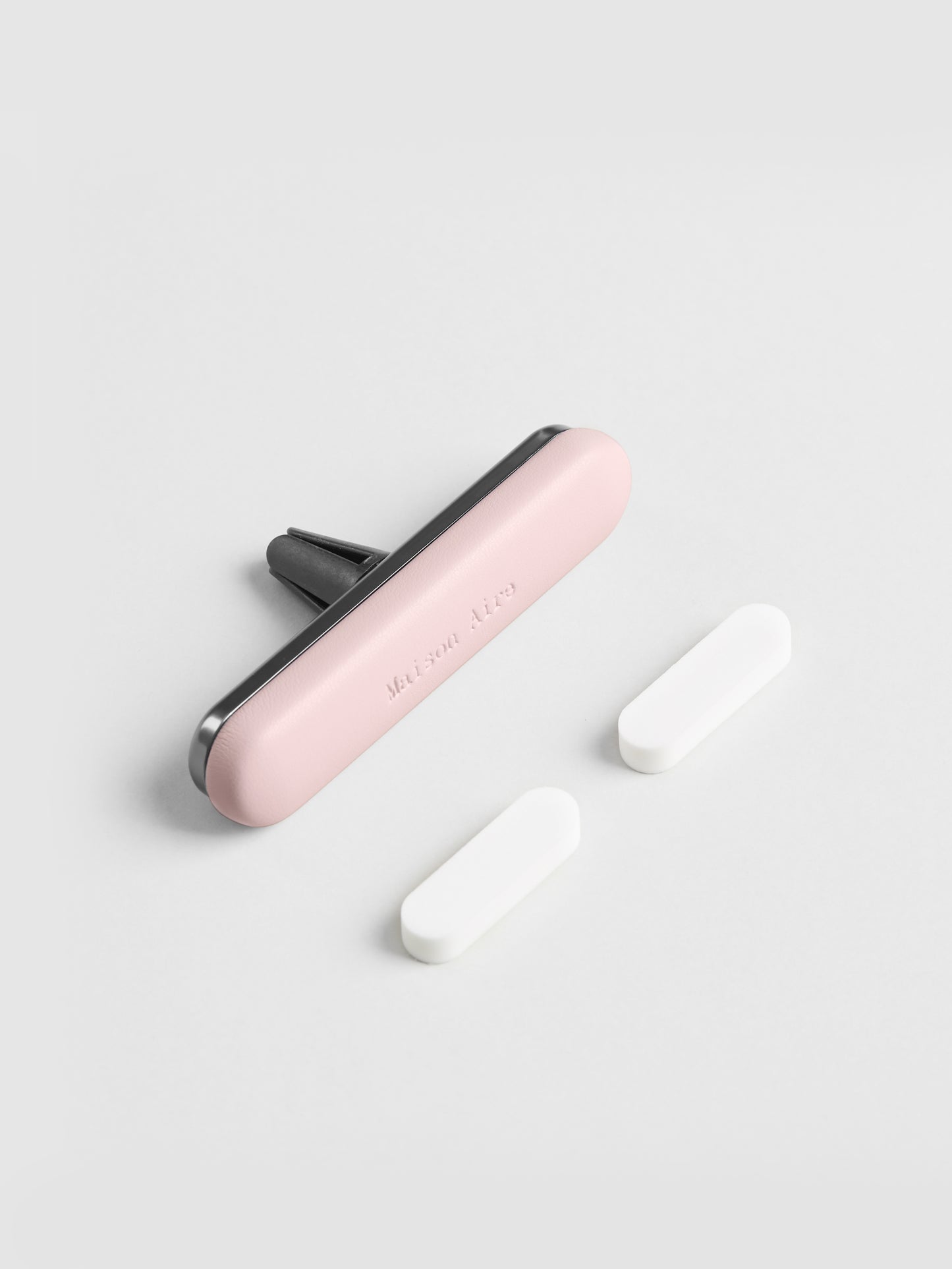 Pink leather Maison Aire car air freshener vent clip air freshener with two white scent refill disks on white background