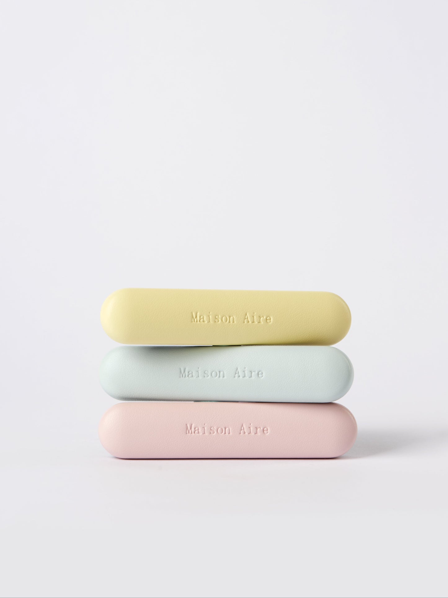 Stack of three pastel leather car freshener  Maison Aire logo on white background