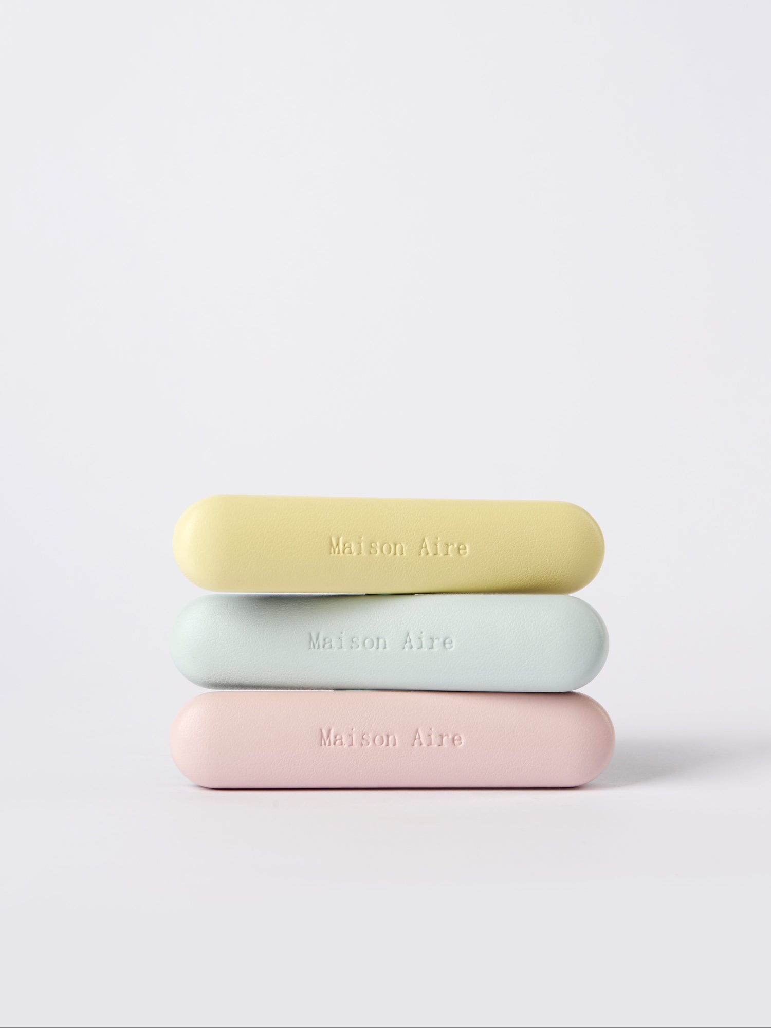 Stack of three pastel leather car freshener  Maison Aire logo on white background