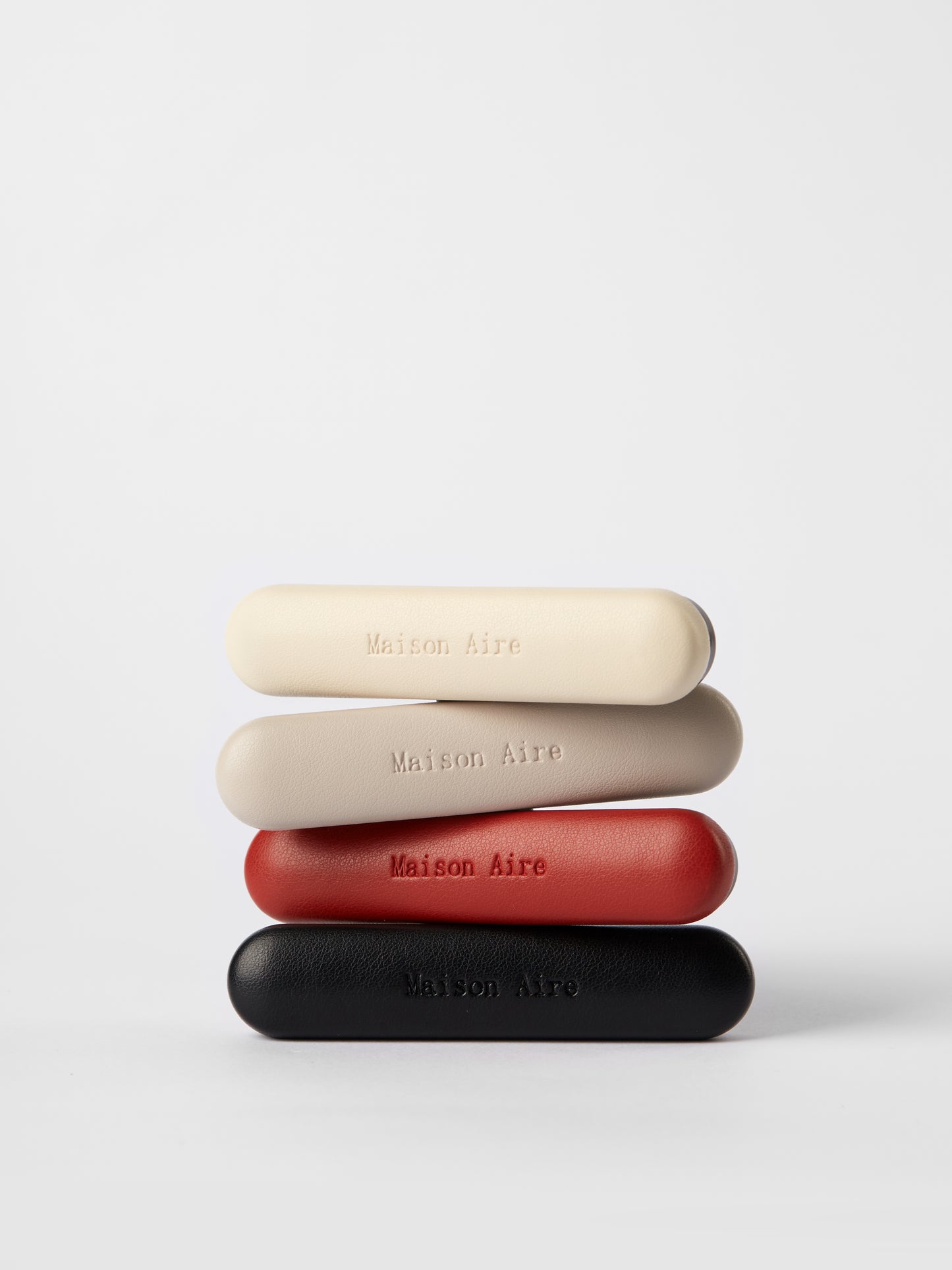 Stack of Maison Aire car air freshener  in beige, light gray, red, and black on white background